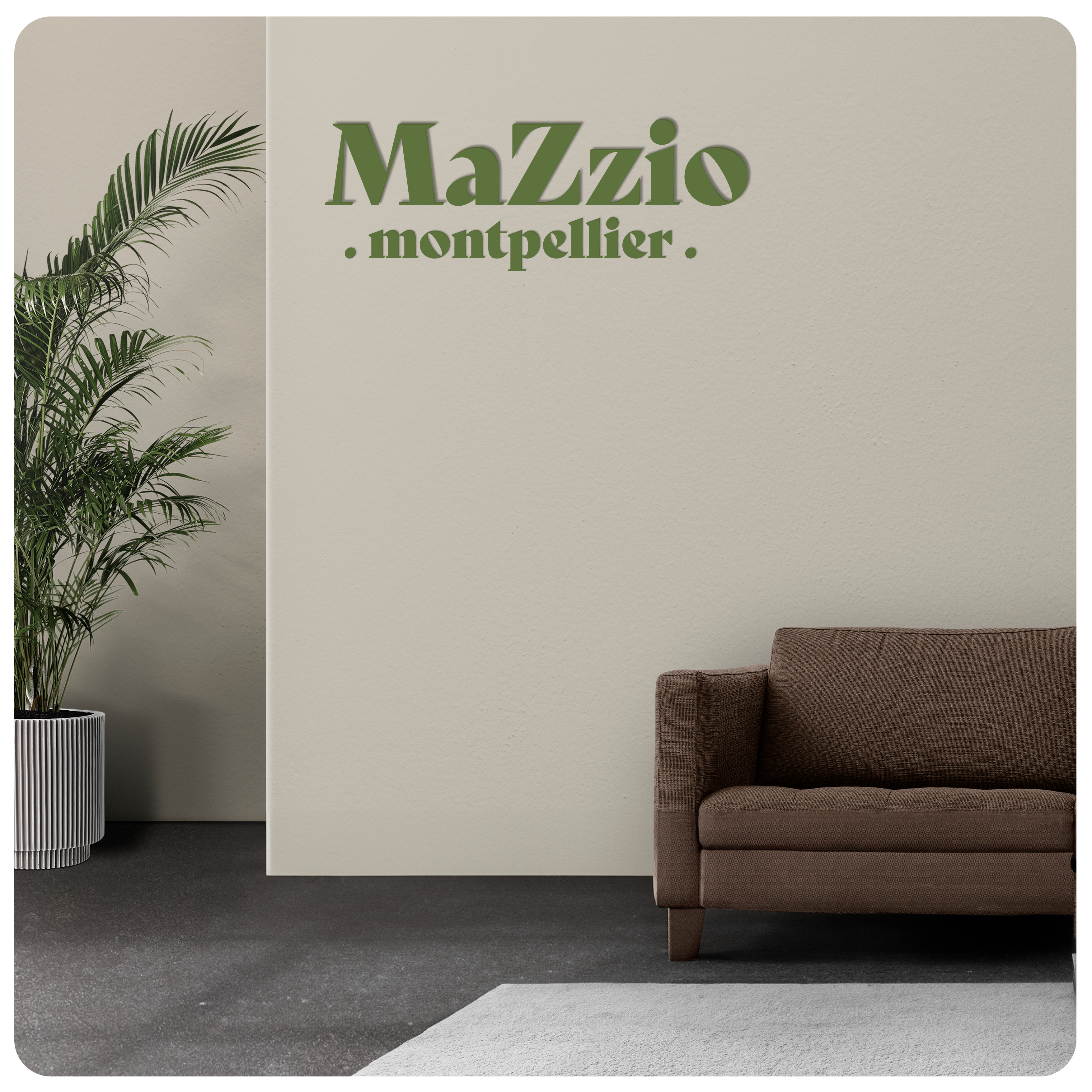 Lettres découpées MaZzio vertes posées sur un mur de couleur blanc cassé dans un hall ou se trouve un canapé marron et une belle plante verte.