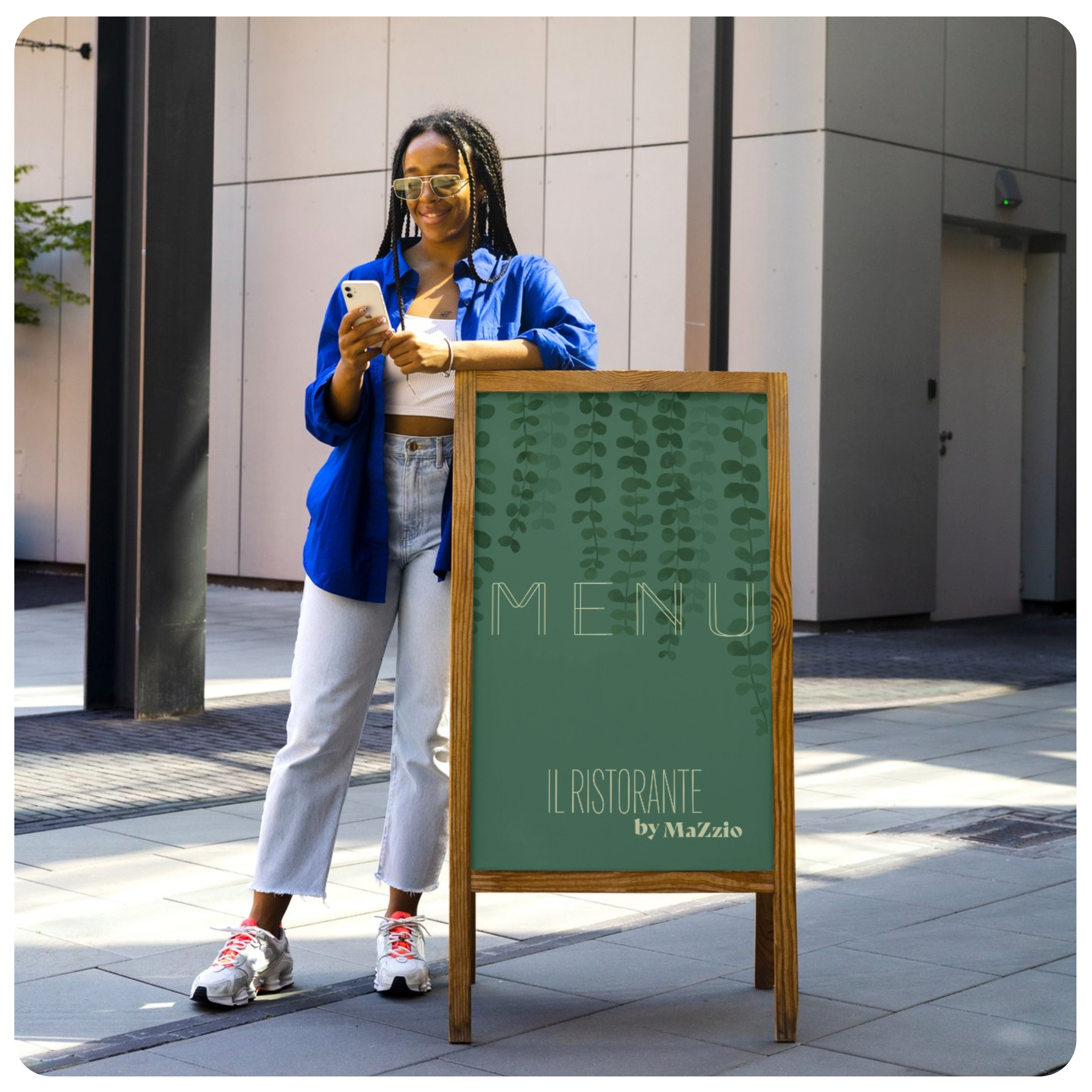 Une femme avec des lunettes de soleil et une chemise bleue est accoudée sur un stop trottoir en bois de couleur marron clair, dans une rue regardant son téléphone avec un visuel vert faisant la publicité d'un restaurant.